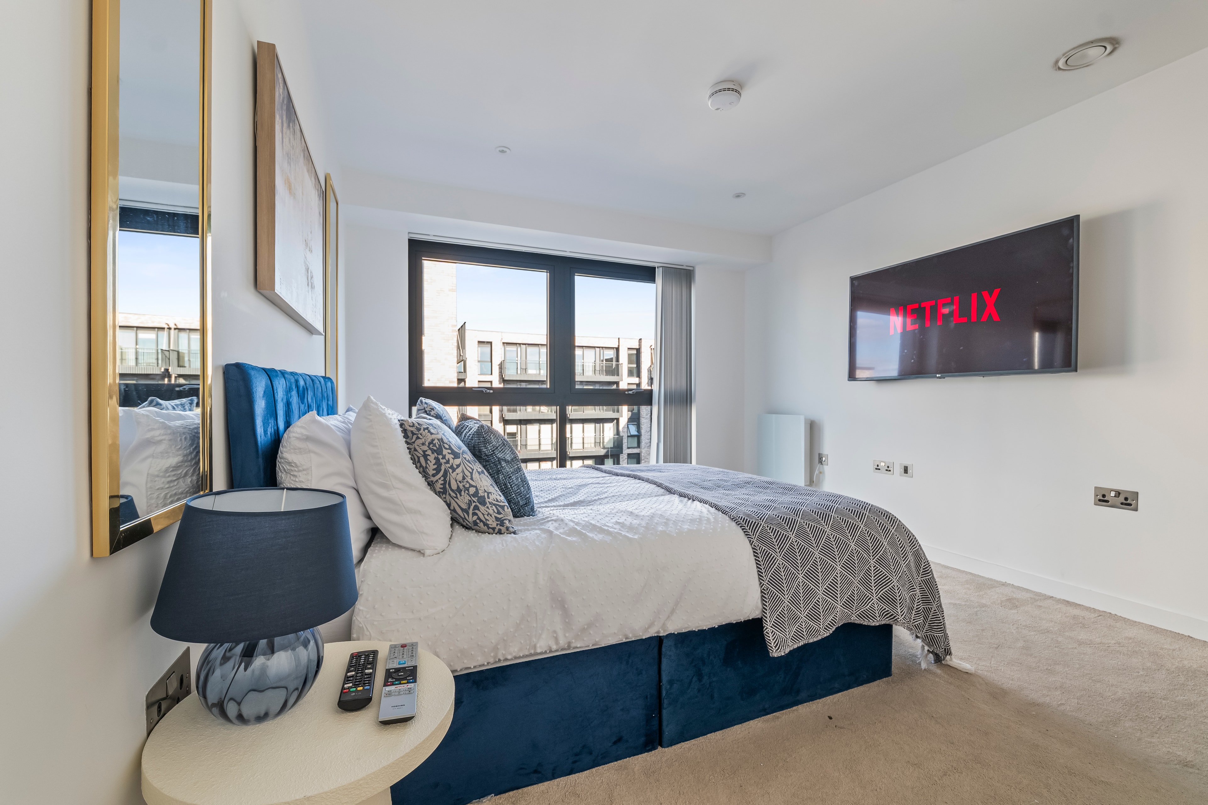 Master bedroom with blue velvet bed and Netflix TV